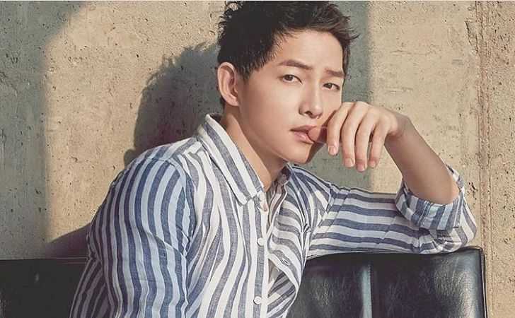 Song Joong-ki posing for a picture in a black-white shirt.