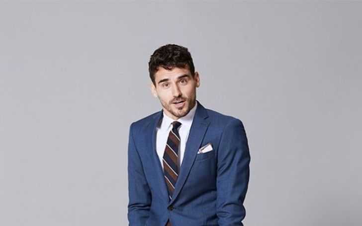Arthur Kulkov poses in blue suit with black tie and white shirt.