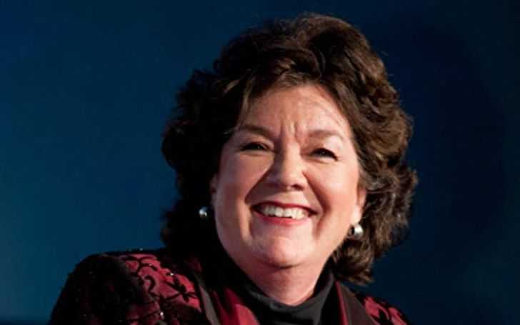 Mary Badham in a red dress smiles at the camera.