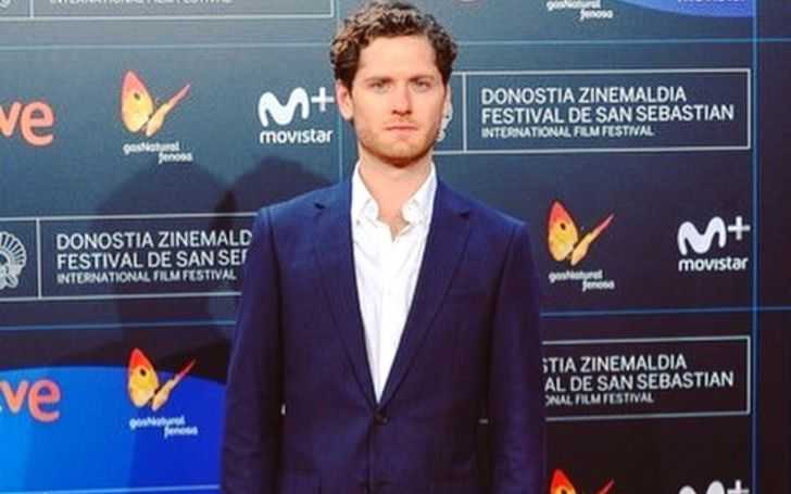 Kyle Soller in a dark blue suit at an event.