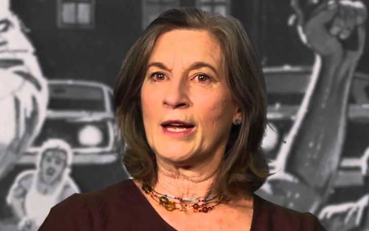 Nancy Kyes in a red dress talking to the audience in an interview.