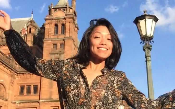 Pisay Pao in a brown dress besides a street lamp.